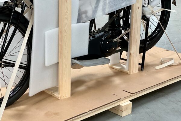 Close-up of motorcycle wheel and footrest protected with foam and secured with straps