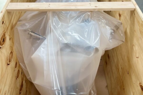 Motorcycle wrapped in clear plastic inside wooden crate