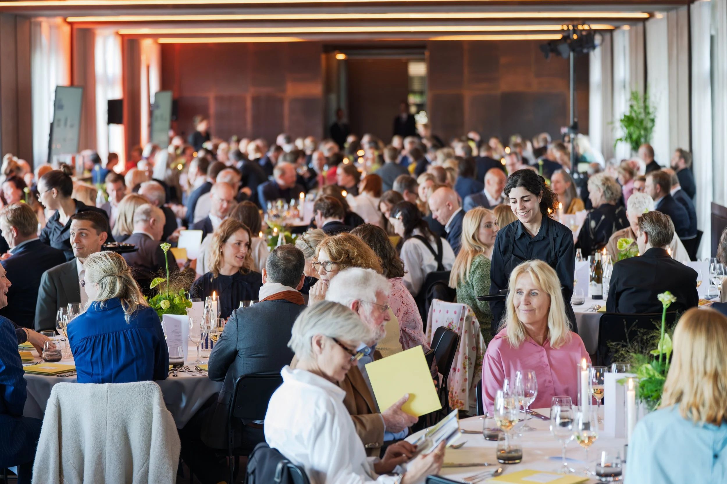 Gæster samlet ved runde borde under Erhvervslivets Kulturpris 2025 med middag, levende lys og festlig stemning.