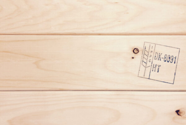 Light heat-treated wood with visible ISPM 15 HT mark (formerly IPPC) and natural knots in the surface.